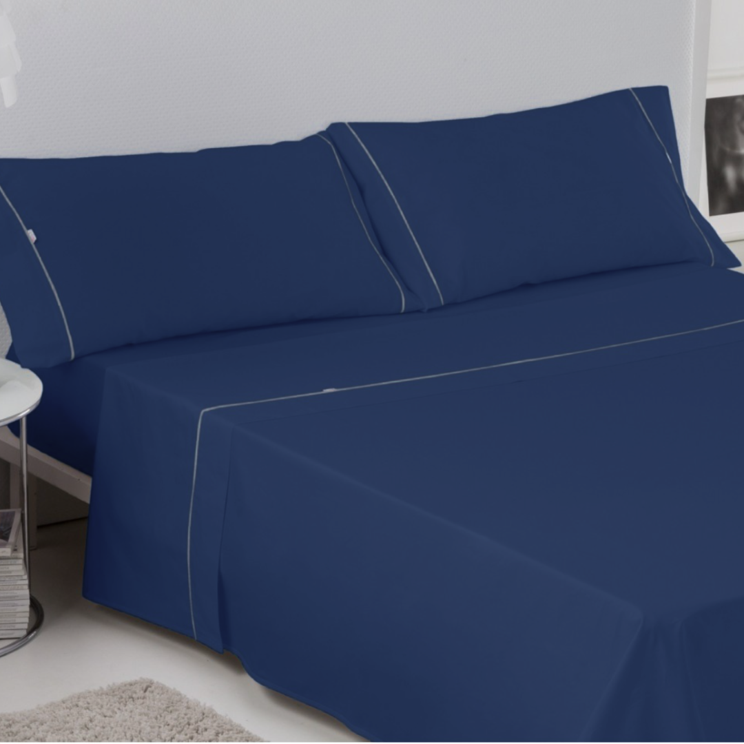 Juego de sábanas azul oscuro en una cama con almohadas